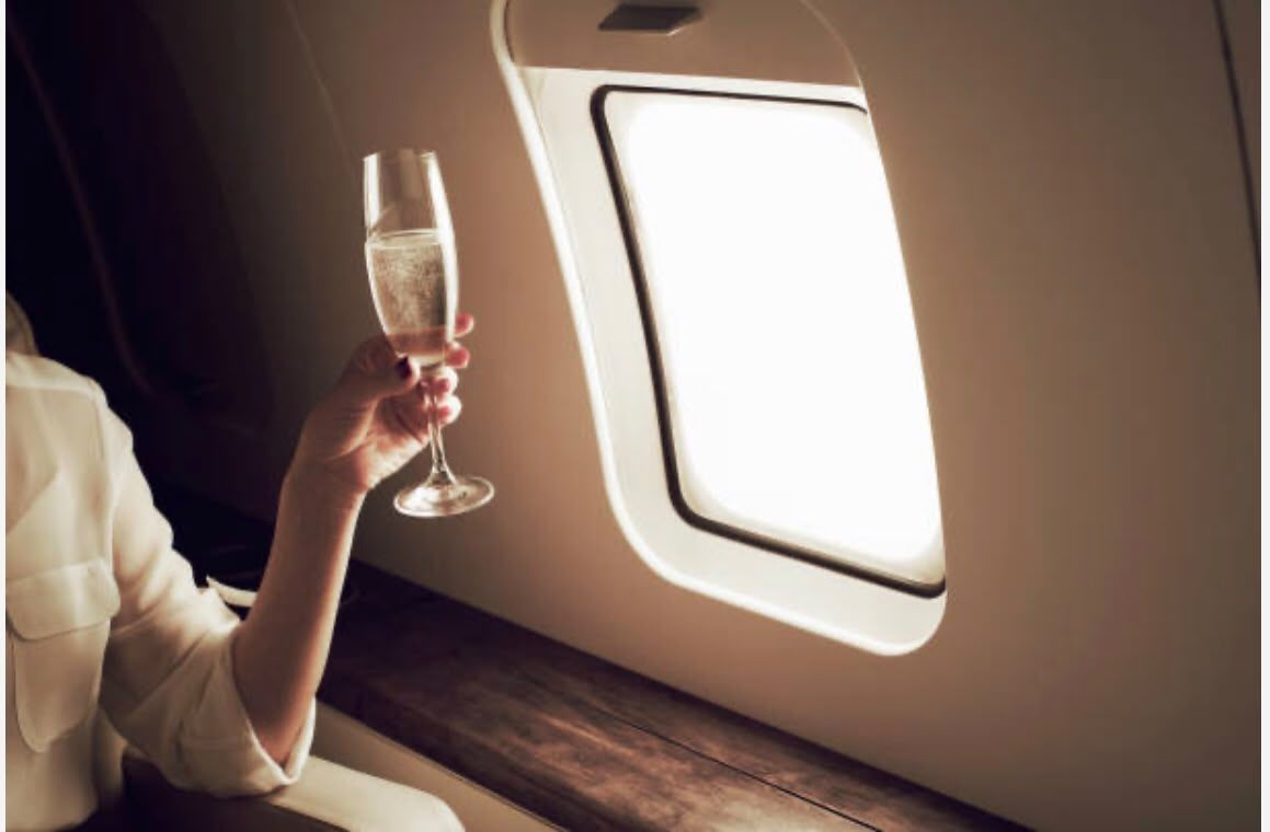 Calice di bollicine accanto all’oblò di un jet privato